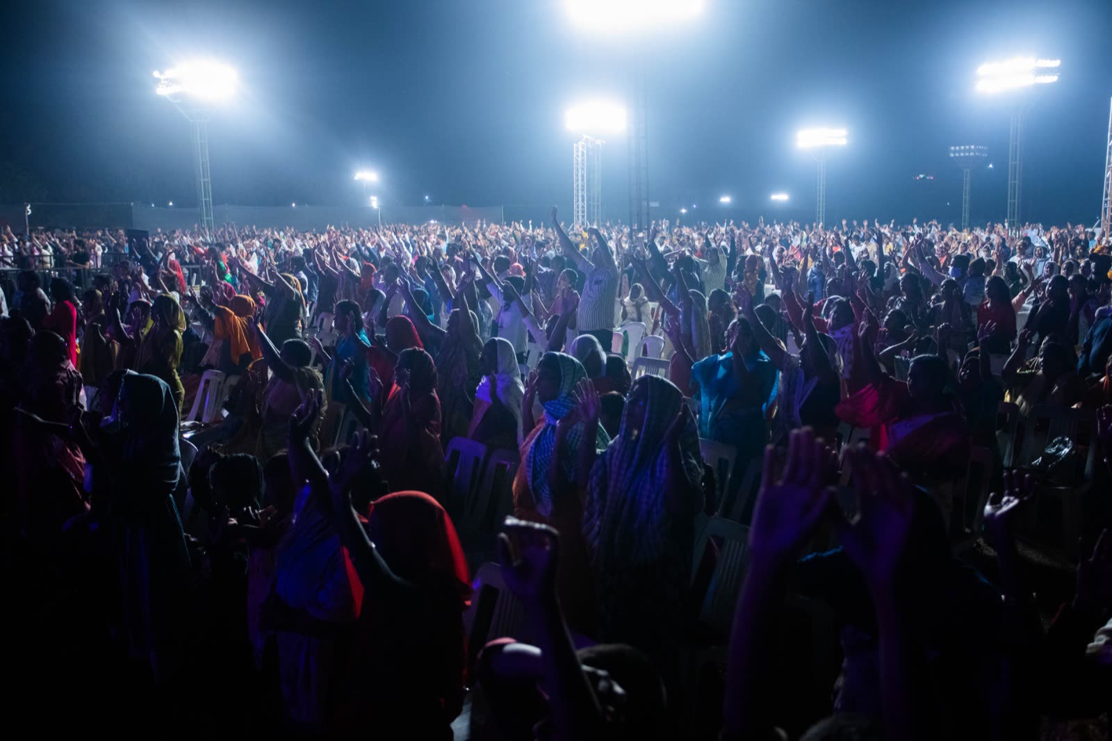 Wide shot of a large crowd with arms raised